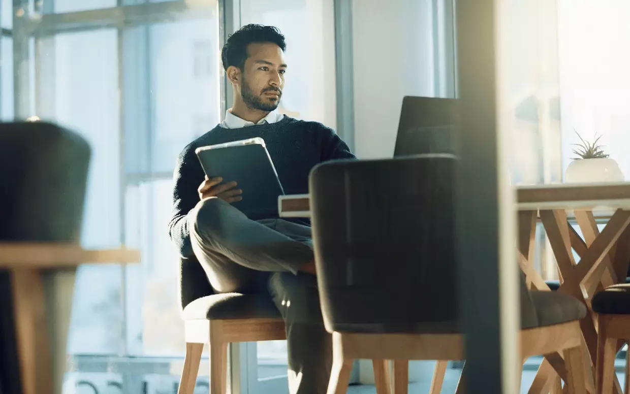 Ein Mann mit verschränkten beinen vor einem Laptop.