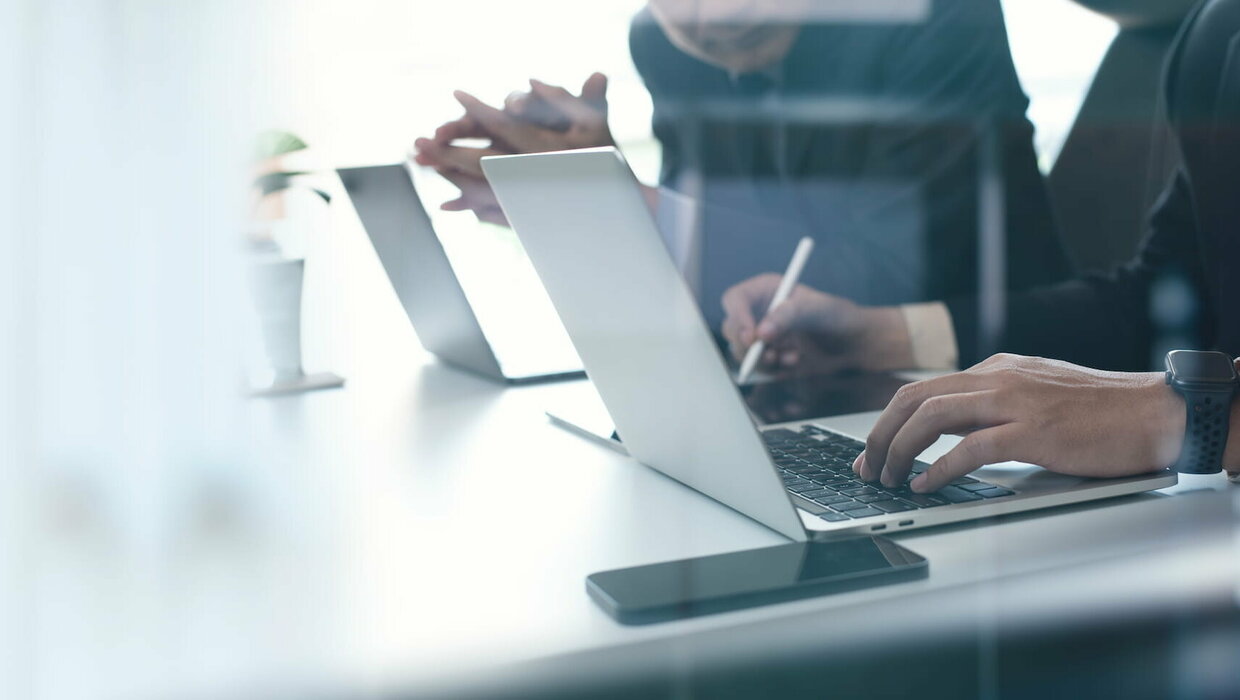 Zwei Männer sitzen vor den Laptops und besprechen sich.