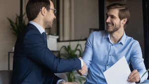 2 Geschäftsmänner machen einen Handshake mit einem Lächeln